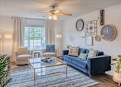 Thumbnail 1 of 27 - A living room with a blue couch and a glass coffee table.