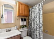 Thumbnail 11 of 35 - A bathroom with a white toilet, sink, and shower curtain.