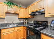 Thumbnail 8 of 35 - A kitchen with wooden cabinets and a black stove top oven.