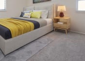 Thumbnail 5 of 8 - a bedroom with a bed and a nightstand with a lamp
