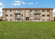 Thumbnail 8 of 8 - a large apartment building with green grass in front of it