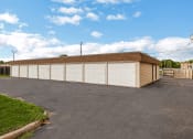 Thumbnail 6 of 8 - a large white garage with a brick roof on a driveway
