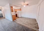 Thumbnail 1 of 13 - an empty living room with a kitchen and a ceiling fan