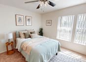 Thumbnail 13 of 33 - A bedroom with a bed, a ceiling fan, and pictures on the wall.
