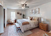 Thumbnail 10 of 33 - A bedroom with a bed, chair, and ceiling fan.