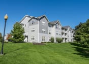Thumbnail 27 of 33 - a large gray apartment building on a green lawn