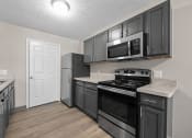 Thumbnail 14 of 33 - a kitchen with black cabinets and stainless steel appliances and a refrigerator