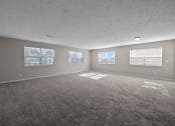 Thumbnail 11 of 33 - an empty living room with a carpeted floor and three windows