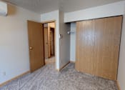 Thumbnail 6 of 16 - A room with a carpeted floor and two wooden doors.