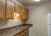 Thumbnail 2 of 16 - A kitchen with wooden cabinets and a granite countertop.