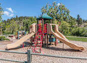 Thumbnail 11 of 16 - A playground with a red and tan slide and a green roofed structure.