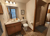 Thumbnail 16 of 28 - A bathroom with a toilet, sink, and mirror.