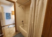 Thumbnail 17 of 28 - A bathroom with a white tub and a white shower curtain.