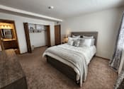 Thumbnail 9 of 28 - A bedroom with a large bed and a wooden headboard.