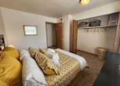 Thumbnail 13 of 28 - A bedroom with a bed covered in yellow and white bedding.