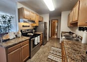 Thumbnail 4 of 28 - A kitchen with brown cabinets and a granite counter top.