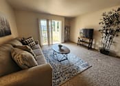 Thumbnail 8 of 28 - A living room with a couch, a coffee table, and a television.