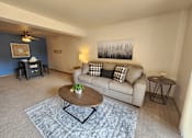Thumbnail 7 of 28 - A living room with a couch, coffee table, and a painting on the wall.