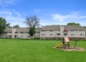 Thumbnail 23 of 28 - a field of green grass and playground outside sun valley apartments