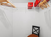 Thumbnail 11 of 29 - a white closet with a chair and a rack on the wall