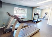 Thumbnail 25 of 30 - A treadmill and a rowing machine are in a spacious room.