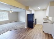 Thumbnail 10 of 30 - A black fridge in a kitchen with wooden floors and white walls.