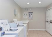 Thumbnail 10 of 16 - a laundry room with four washes and a dryer