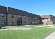 Thumbnail 12 of 12 - a large brick building with a grassy area in front of it