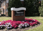 Thumbnail 10 of 10 - a sign for the district apartment homes in front of flowers