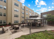 Thumbnail 26 of 34 - an outdoor patio with a firepit and gazebo in front of an apartment building