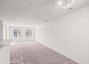 Thumbnail 5 of 25 - A large empty room with carpeted floor and two windows.
