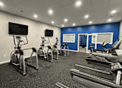 Thumbnail 14 of 26 - A gym with treadmills, exercise bikes, and a television.