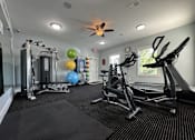 Thumbnail 23 of 31 - A spacious gym with a variety of equipment including a treadmill, a stationary bike, a rowing machine, a weight machine, and a bench press.