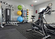 Thumbnail 22 of 31 - A gym with a rowing machine, a bench, and a wall-mounted clock.