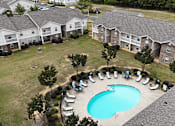 Thumbnail 23 of 29 - An aerial view of a swimming pool surrounded by chairs and trees in a residential area.