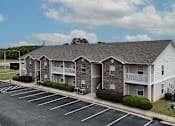 Thumbnail 24 of 29 - A large apartment complex with a parking lot in front.