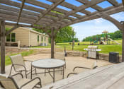 Thumbnail 23 of 27 - a patio with a table and chairs and a playground in the background