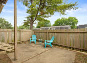 Thumbnail 18 of 27 - a patio with two blue chairs and a table in front of a fence