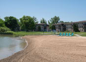 Thumbnail 16 of 26 - a beach with chairs near a body of water and buildings