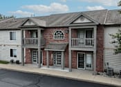 Thumbnail 32 of 35 - A two-story brick building with a grey roof and a balcony on the second floor.