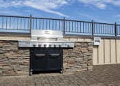Thumbnail 15 of 23 - an outdoor barbecue grill with a stone wall and a metal railing