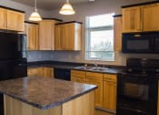 Thumbnail 3 of 23 - a kitchen with wooden cabinets and black appliances