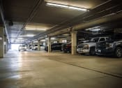 Thumbnail 12 of 23 - a parking garage filled with cars at apartment complex