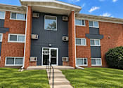 Thumbnail 5 of 9 - A red brick building with a black door and windows.