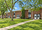Thumbnail 3 of 9 - A tree in front of a brick building with a walkway in between.