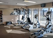 Thumbnail 1 of 7 - A gym with a row of exercise bikes and a television on the wall.