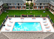 Thumbnail 23 of 34 - A swimming pool surrounded by lounge chairs and a brick building.