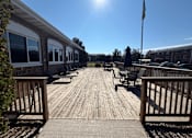 Thumbnail 25 of 26 - A wooden deck with chairs and a flag on a sunny day.