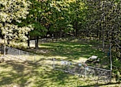 Thumbnail 14 of 26 - A fenced-in area with a picnic table in the middle of a grassy field.