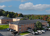 Thumbnail 17 of 26 - A large brick building with a parking lot in front.